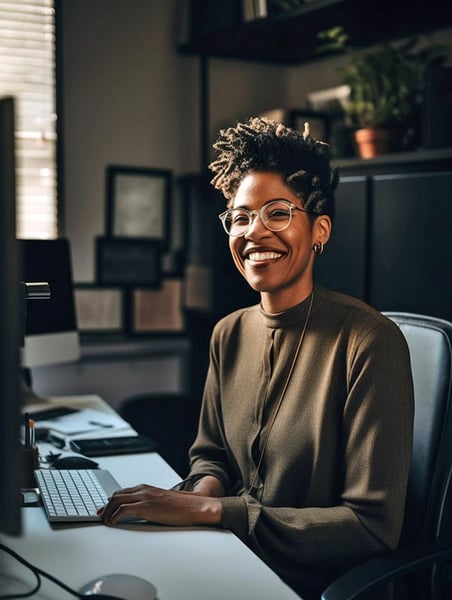 Woman sitting at her desk smiling in front of her computer in her home office.
